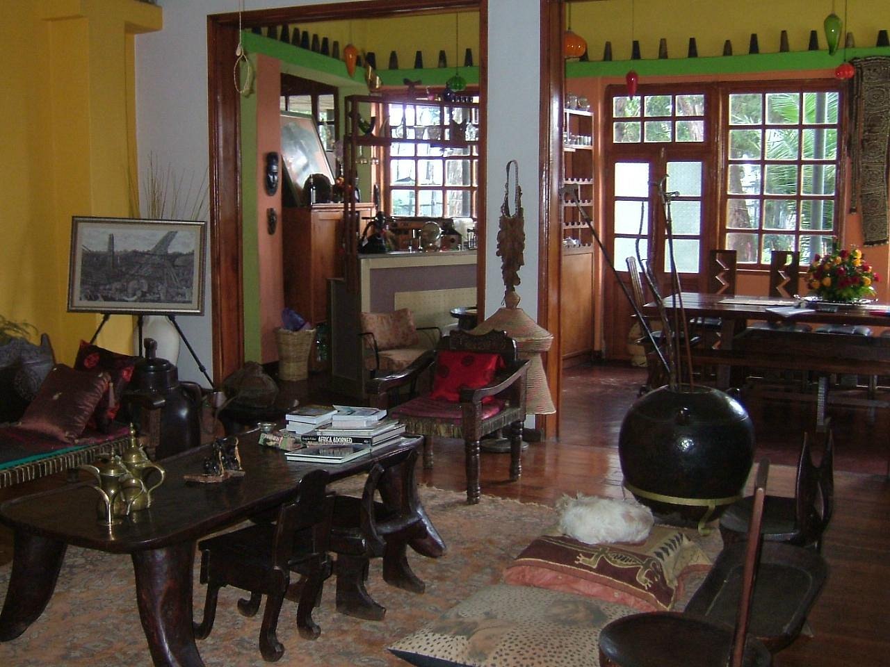 Traditional Ethiopian living room with golden walls, handcrafted wooden furniture, colorful textiles, ornate mirror, and authentic cultural artifacts creating a warm, historic atmosphere